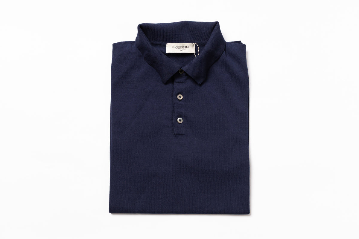 Folded navy blue polo shirt with a brand label on a white background