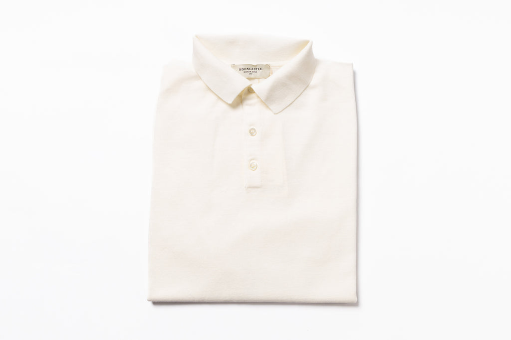 Folded cream-colored polo shirt on a white background