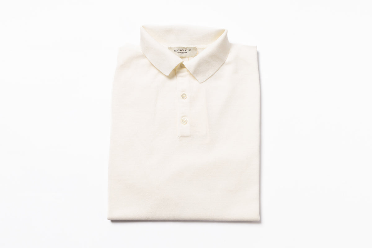 Folded cream-colored polo shirt on a white background