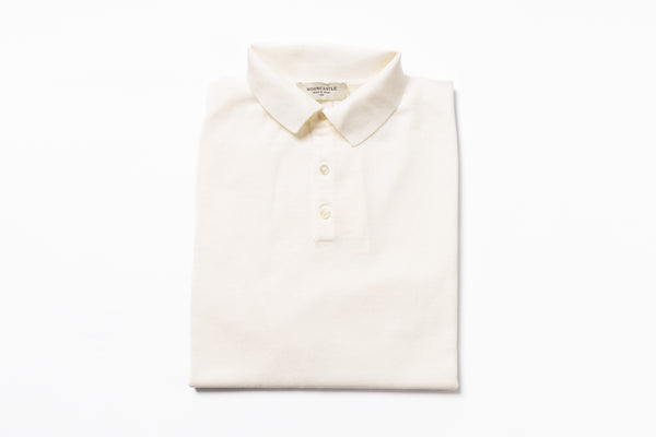 Folded cream-colored polo shirt on a white background