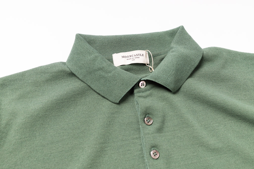 Green polo shirt with a tag on a white background