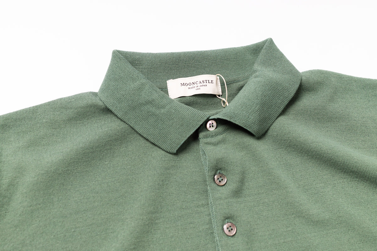 Green polo shirt with a tag on a white background