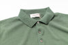 Green polo shirt with a tag on a white background