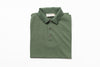 Folded green polo shirt with a brand label on a white background