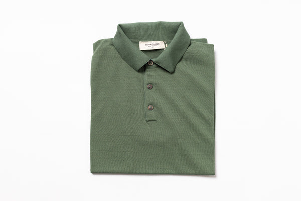 Folded green polo shirt with a brand label on a white background