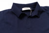 Navy blue polo shirt with a tag on a white background