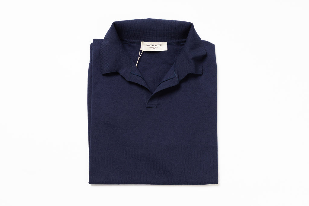 Folded navy blue polo shirt with a brand label on a white background