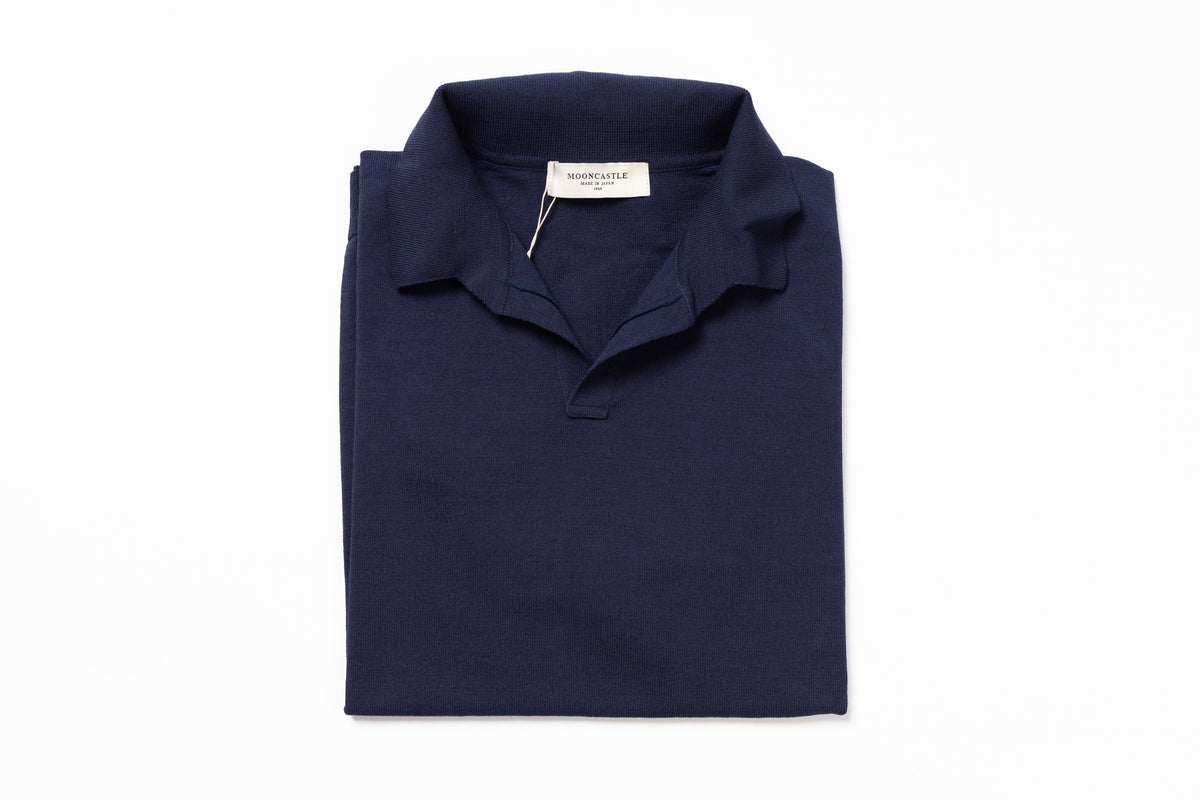 Folded navy blue polo shirt with a brand label on a white background