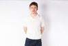 Man wearing a white polo shirt and dark jeans against a white background