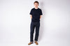 Person wearing a black t-shirt and blue jeans standing against a white background