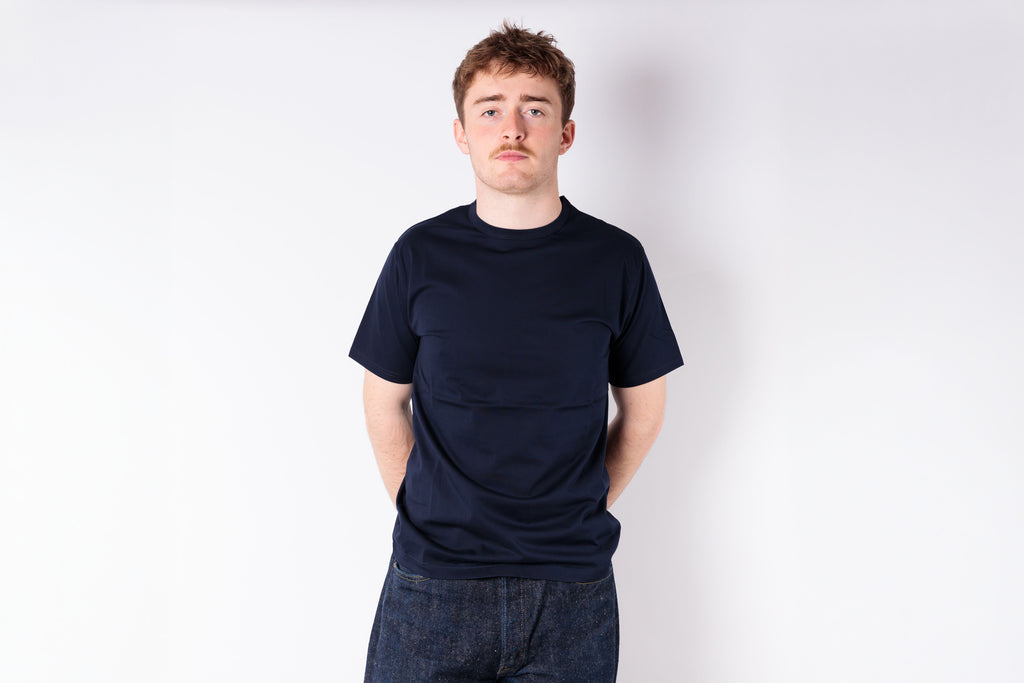 Person wearing a black t-shirt and dark jeans against a white background