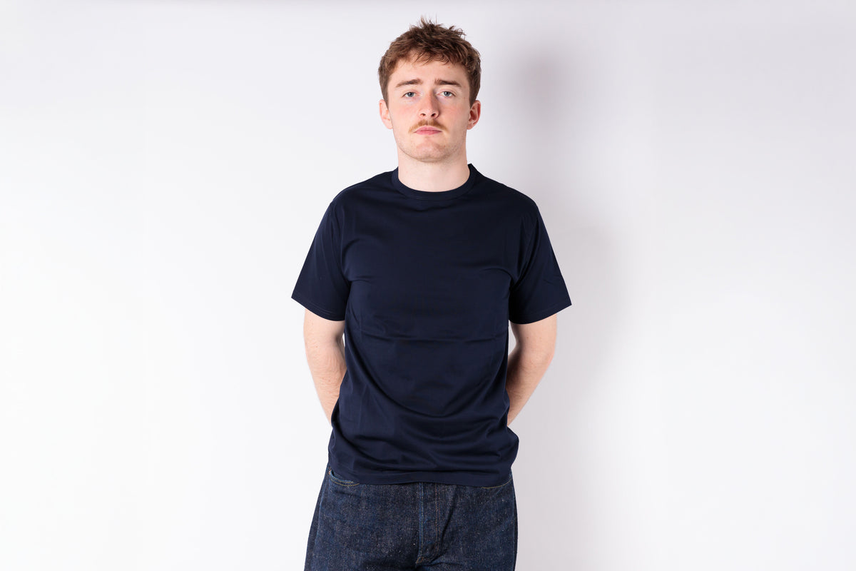 Person wearing a black t-shirt and dark jeans against a white background