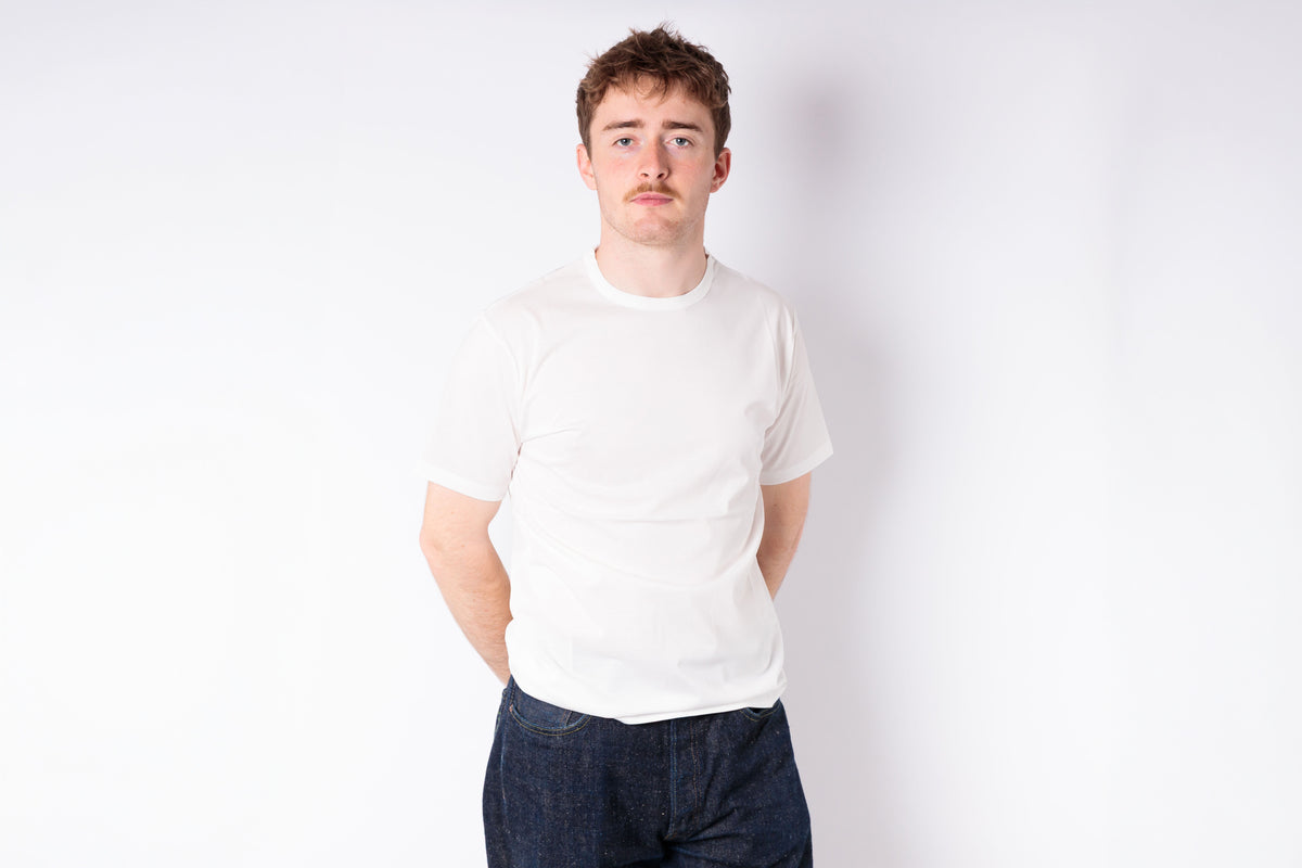 Person wearing a plain white t-shirt and dark pants on a white background