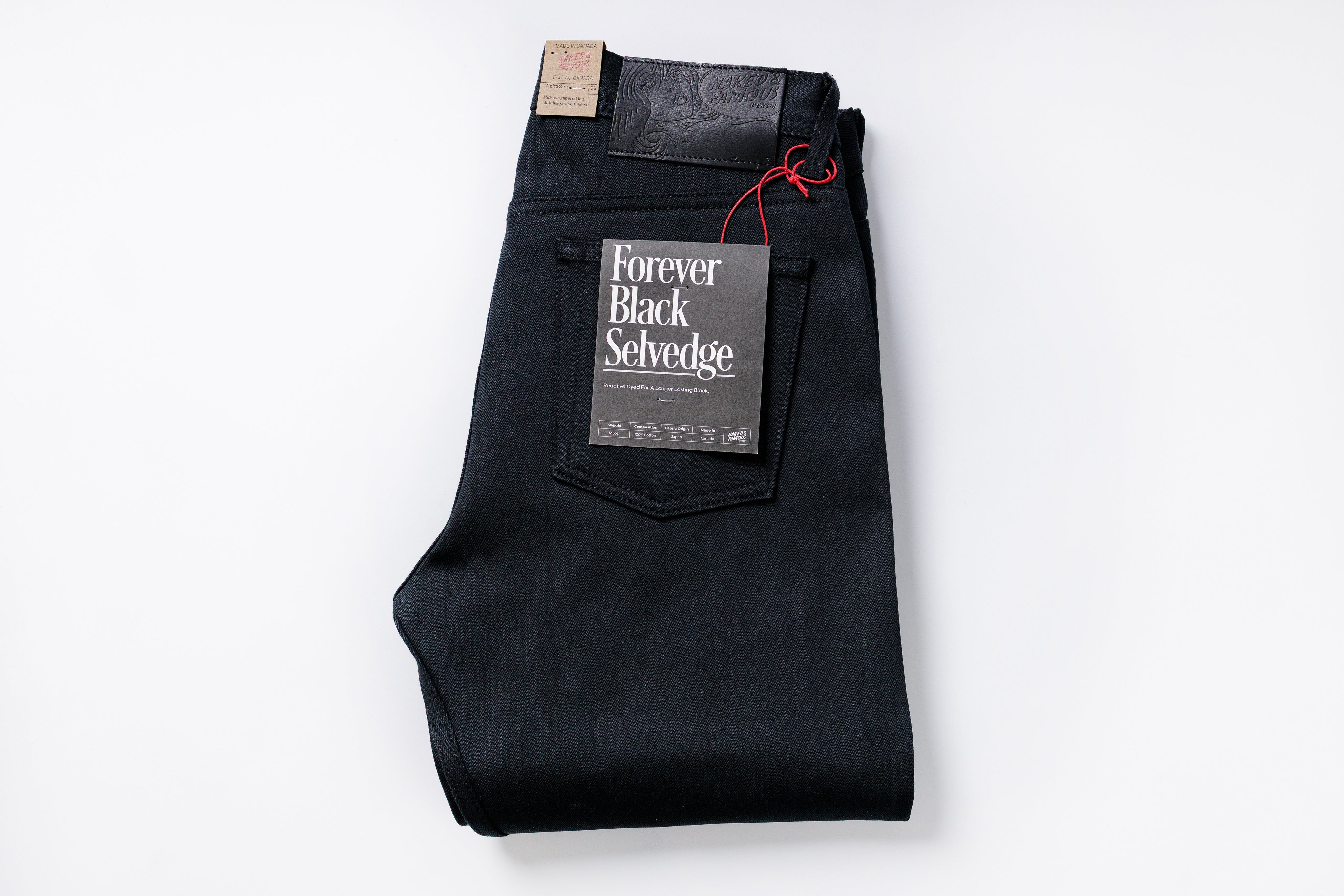 Folded black selvedge jeans with a label on a white background