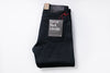Folded black selvedge jeans with a label on a white background