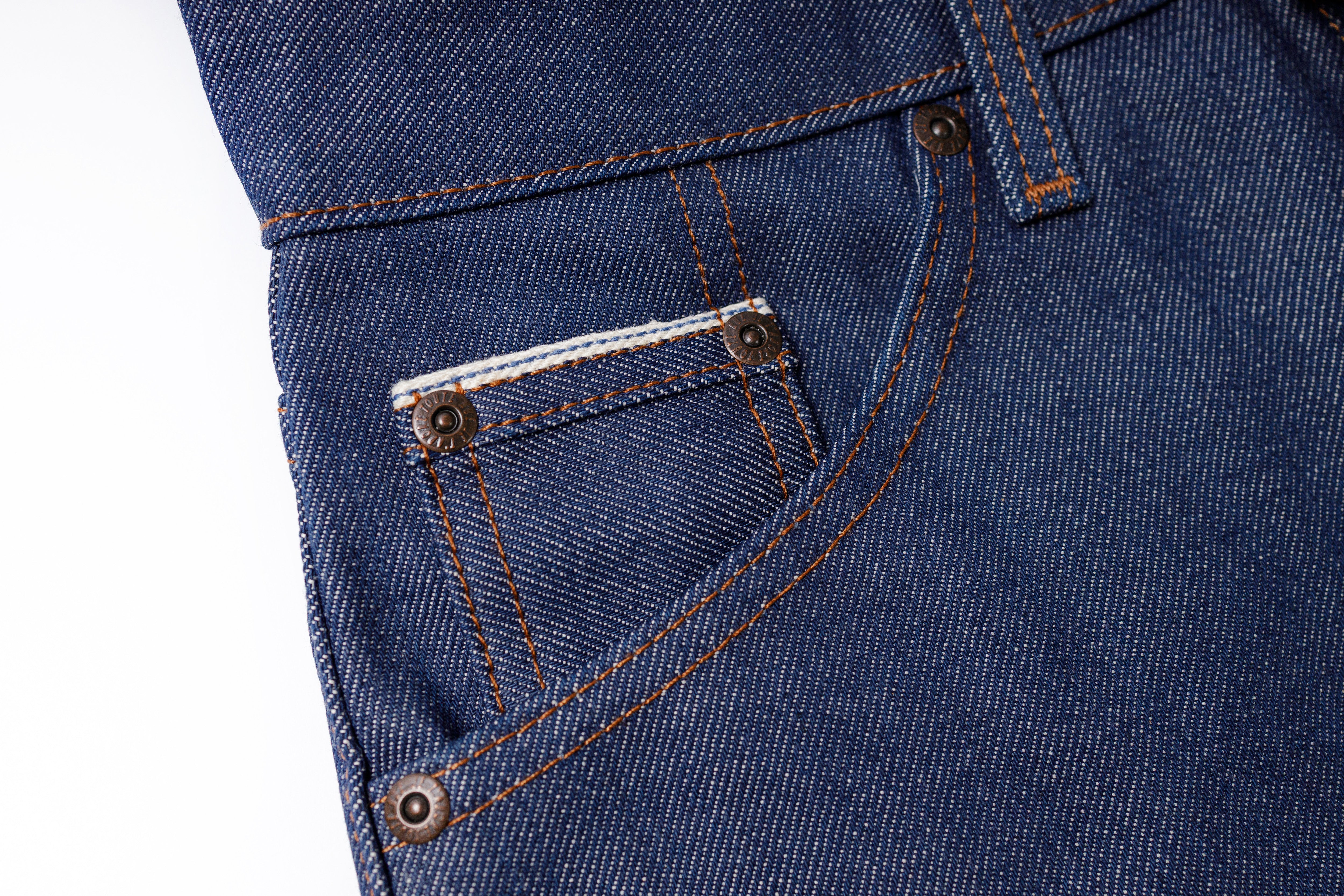 Close-up of blue denim jeans with stitching details on a white background