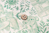 A close-up of a light brown four-hole button resting on a cream-colored fabric with a green botanical and animal print.