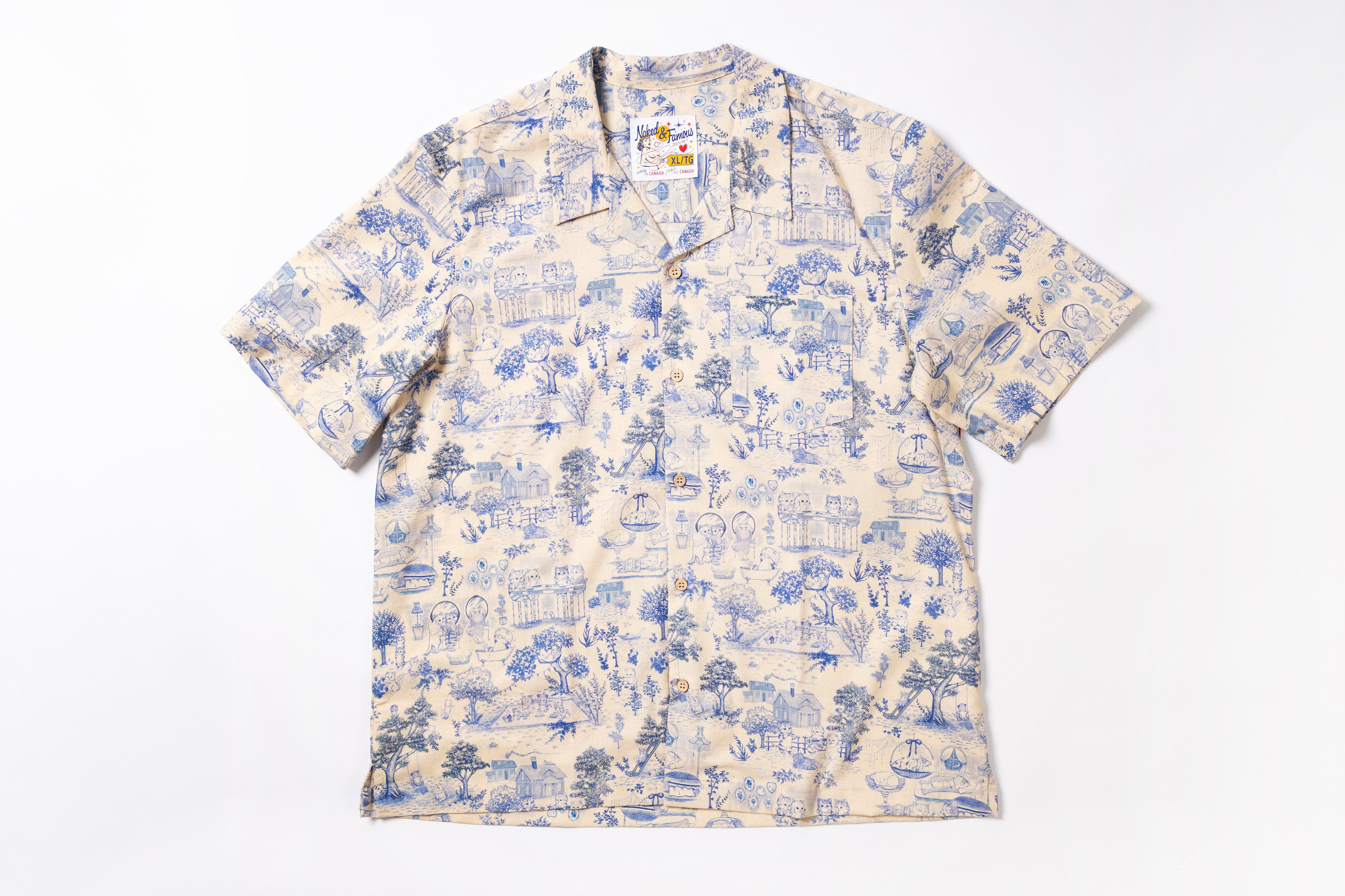 A short-sleeve camp collar button-up shirt with an all-over blue toile-style print on a cream background, laid flat against a white background.