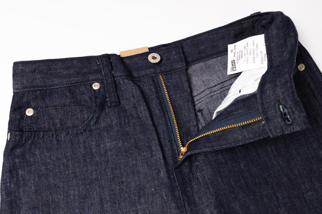 Close-up of a pair of dark blue jeans with a brand label on a white background