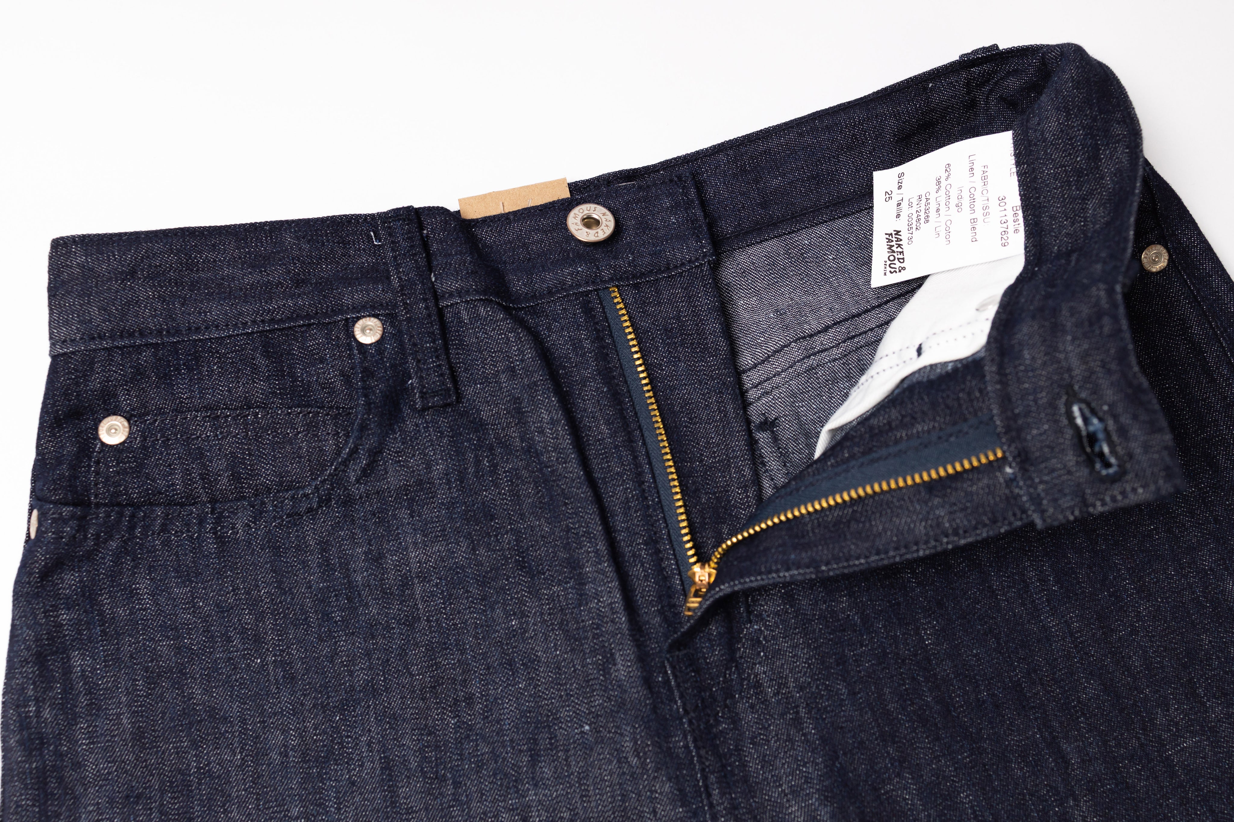 Close-up of a pair of dark blue jeans with a brand label on a white background