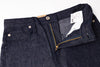 Close-up of a pair of dark blue jeans with a brand label on a white background