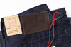 Close-up of dark blue jeans with a brand label and tag on a white background