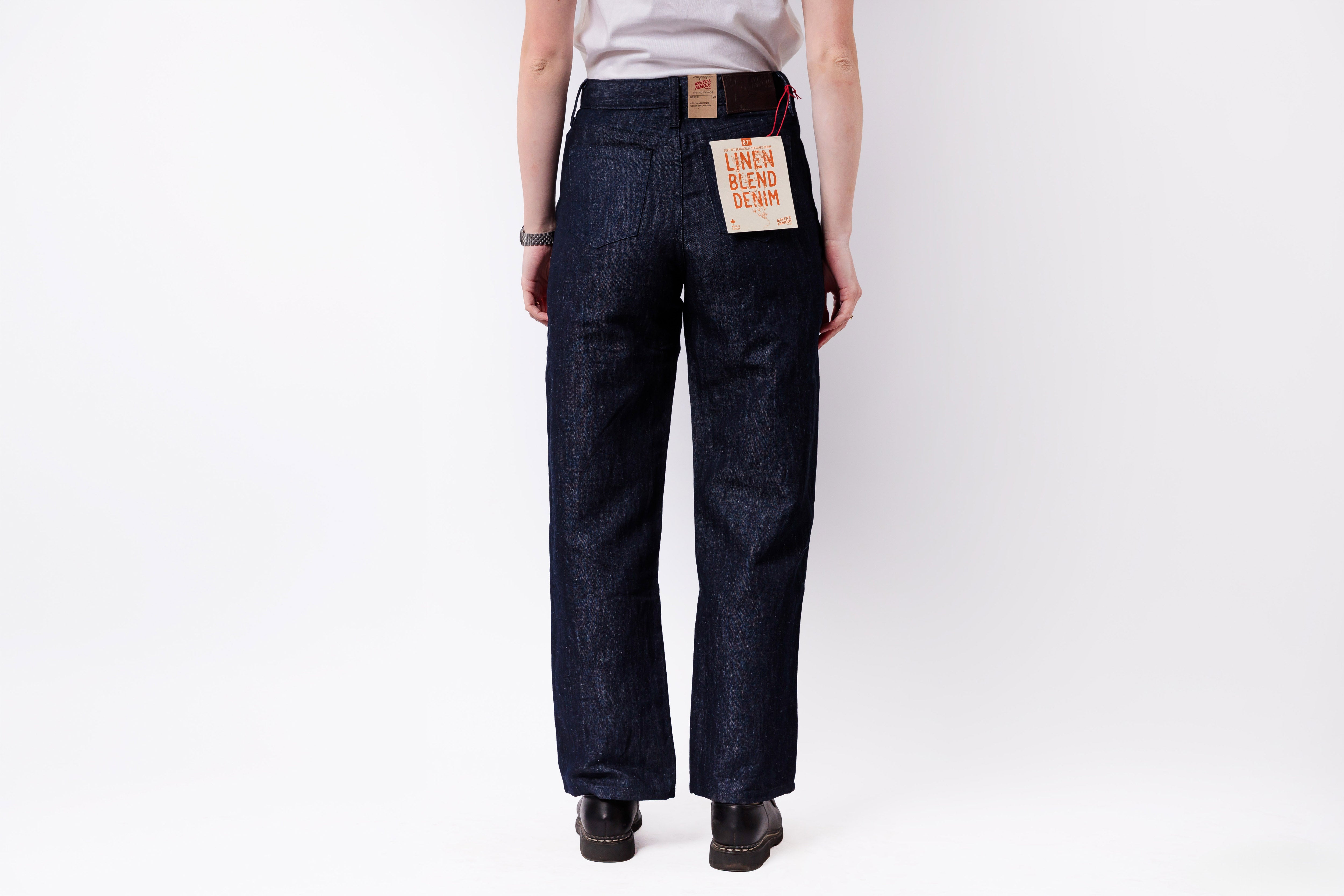 Person wearing dark blue jeans with a visible brand tag on a white background
