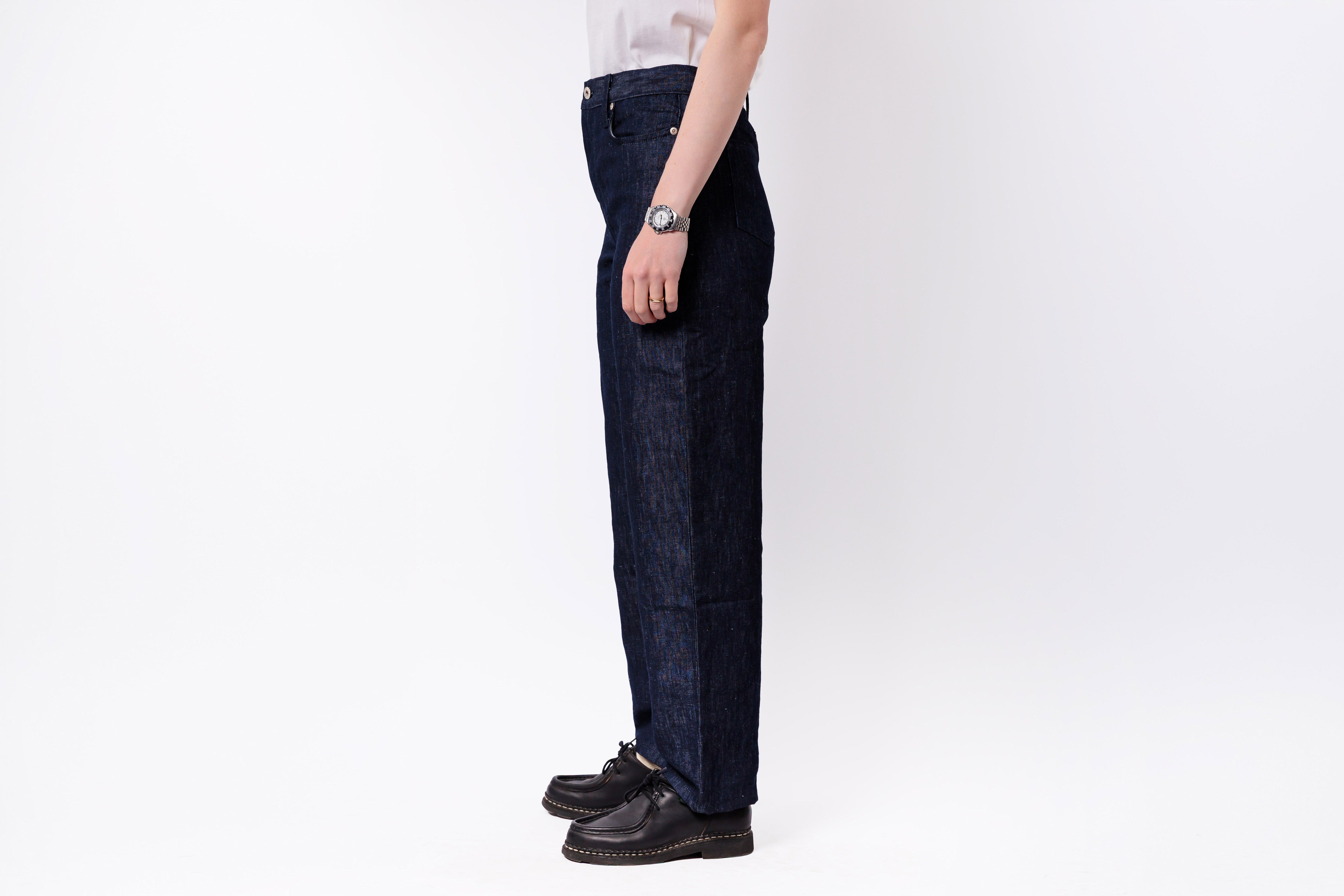 Person wearing dark blue jeans and black shoes on a white background
