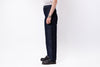 Person wearing dark blue jeans and black shoes on a white background