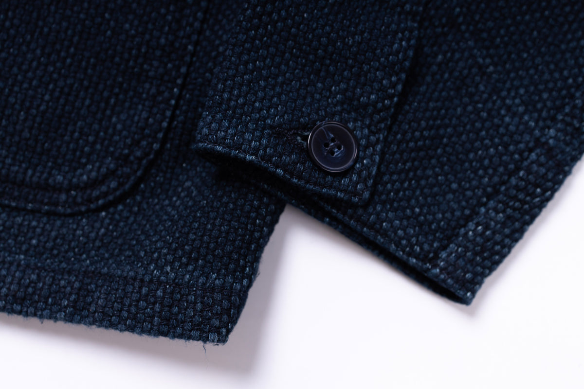Close-up of a dark blue textured fabric with a button on a white background