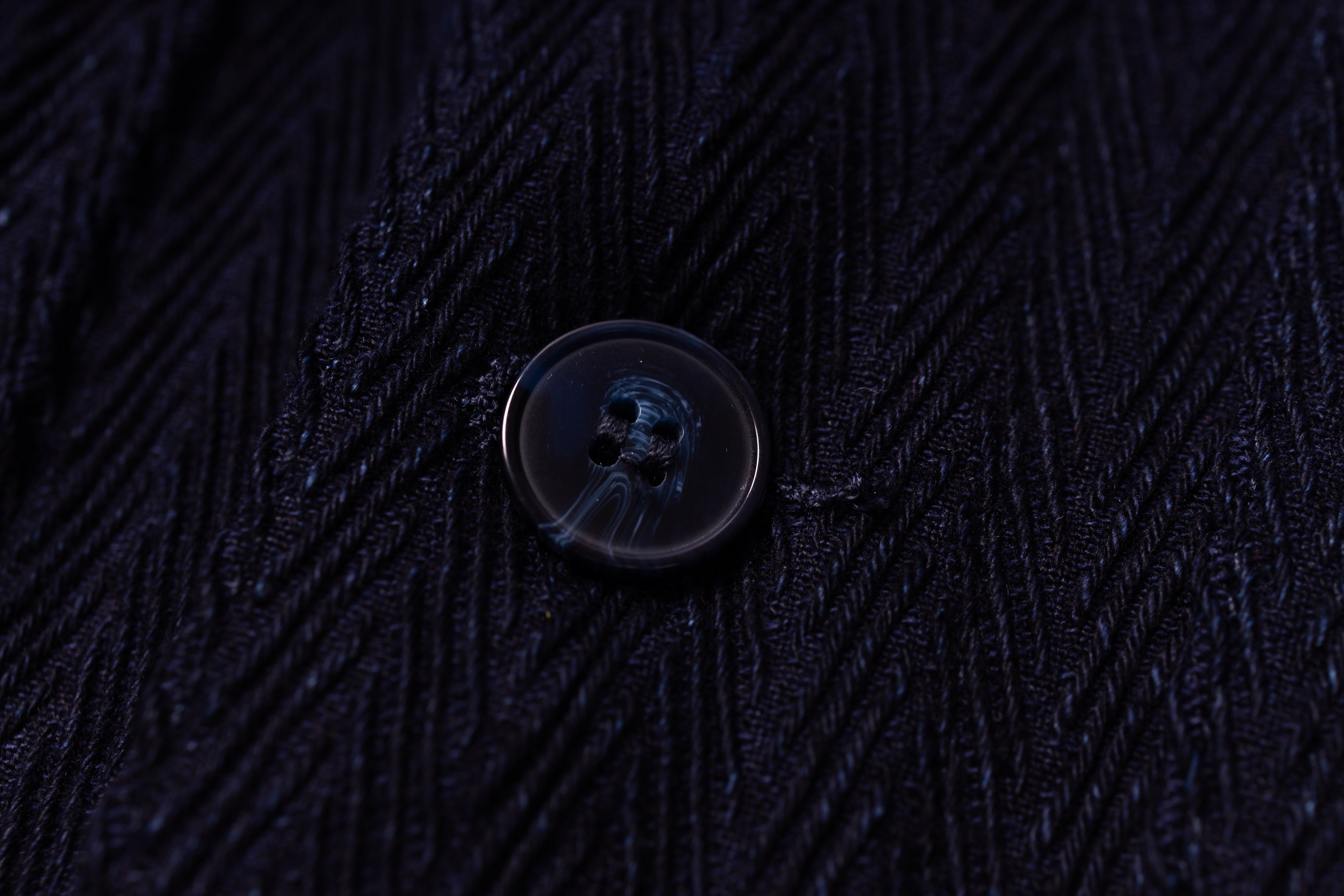 Close-up of a button on dark textured fabric