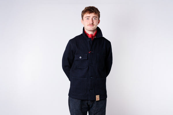 Man wearing a dark blue jacket over a red shirt on a white background