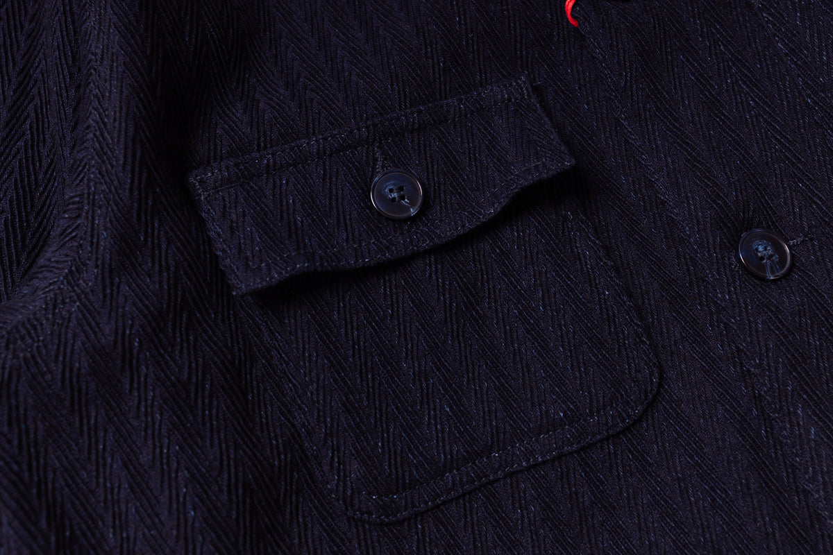 Close-up of a dark textured fabric with buttons and a pocket