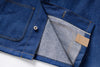 Close-up of a blue denim jacket with a button and label on a white background