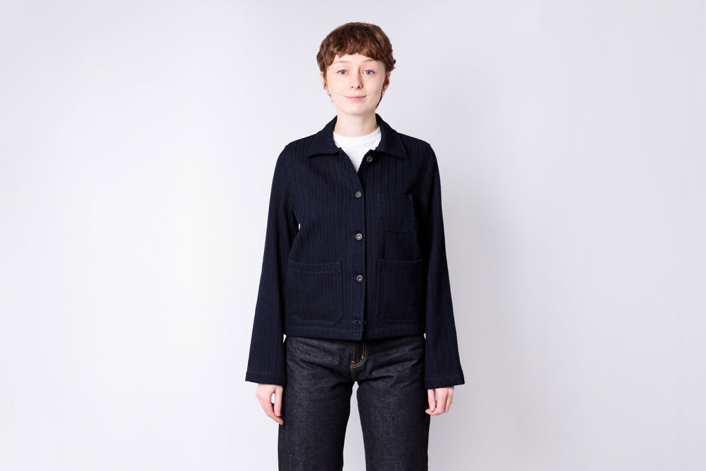 Person wearing a dark jacket and jeans on a white background