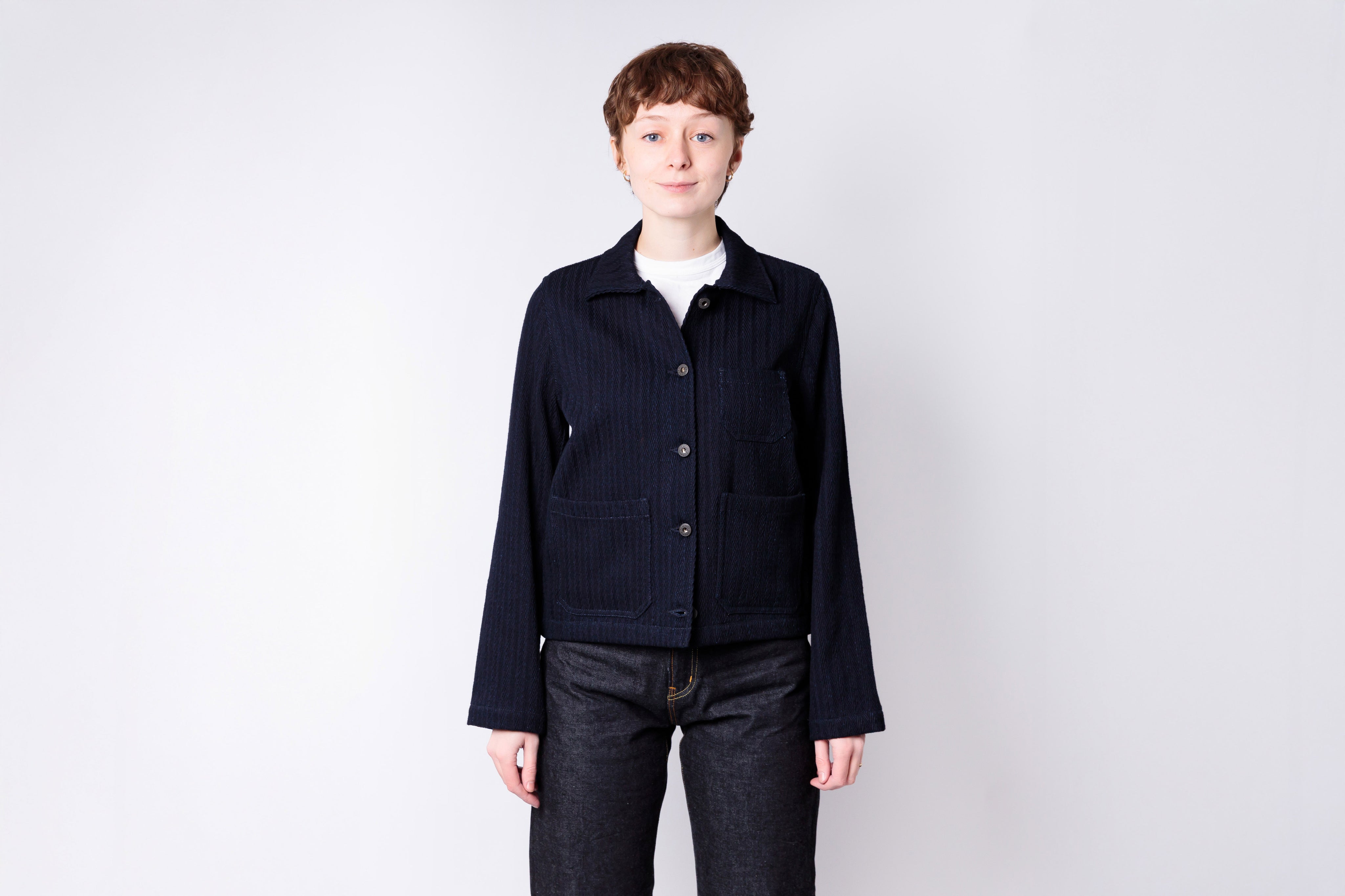 Person wearing a dark jacket and jeans on a white background