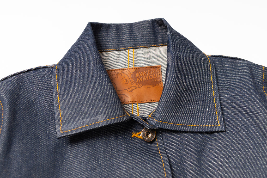 Close-up of a denim jacket collar with a brand label on a white background
