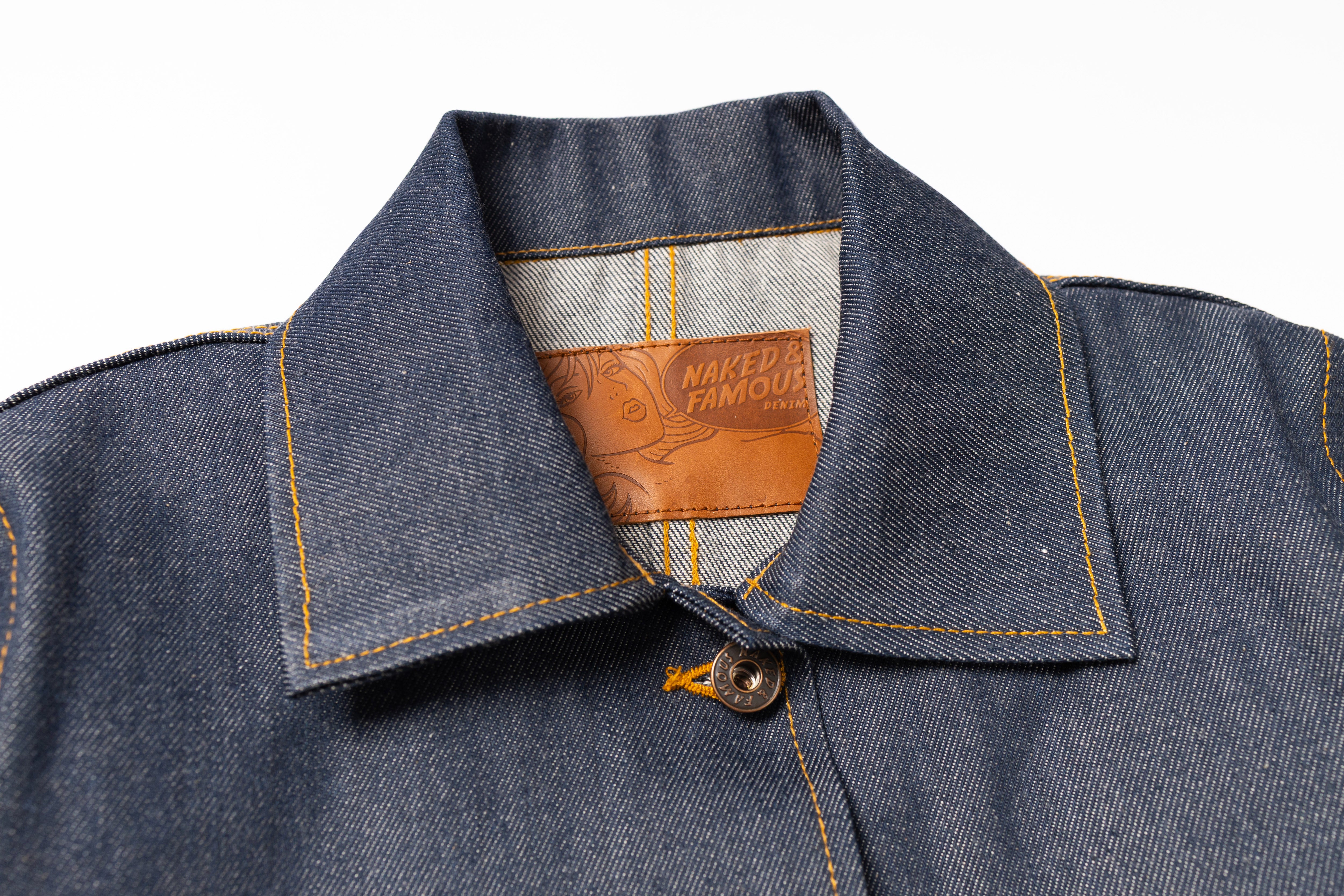 Close-up of a denim jacket collar with a brand label on a white background