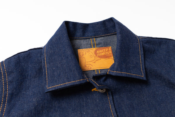 Close-up of a blue denim jacket with a brand label on a white background