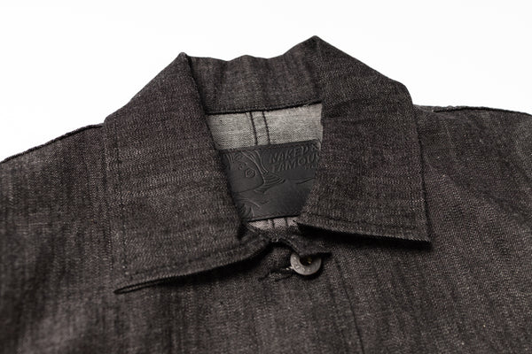 Close-up of a dark gray coat with a collar and brand label on a white background