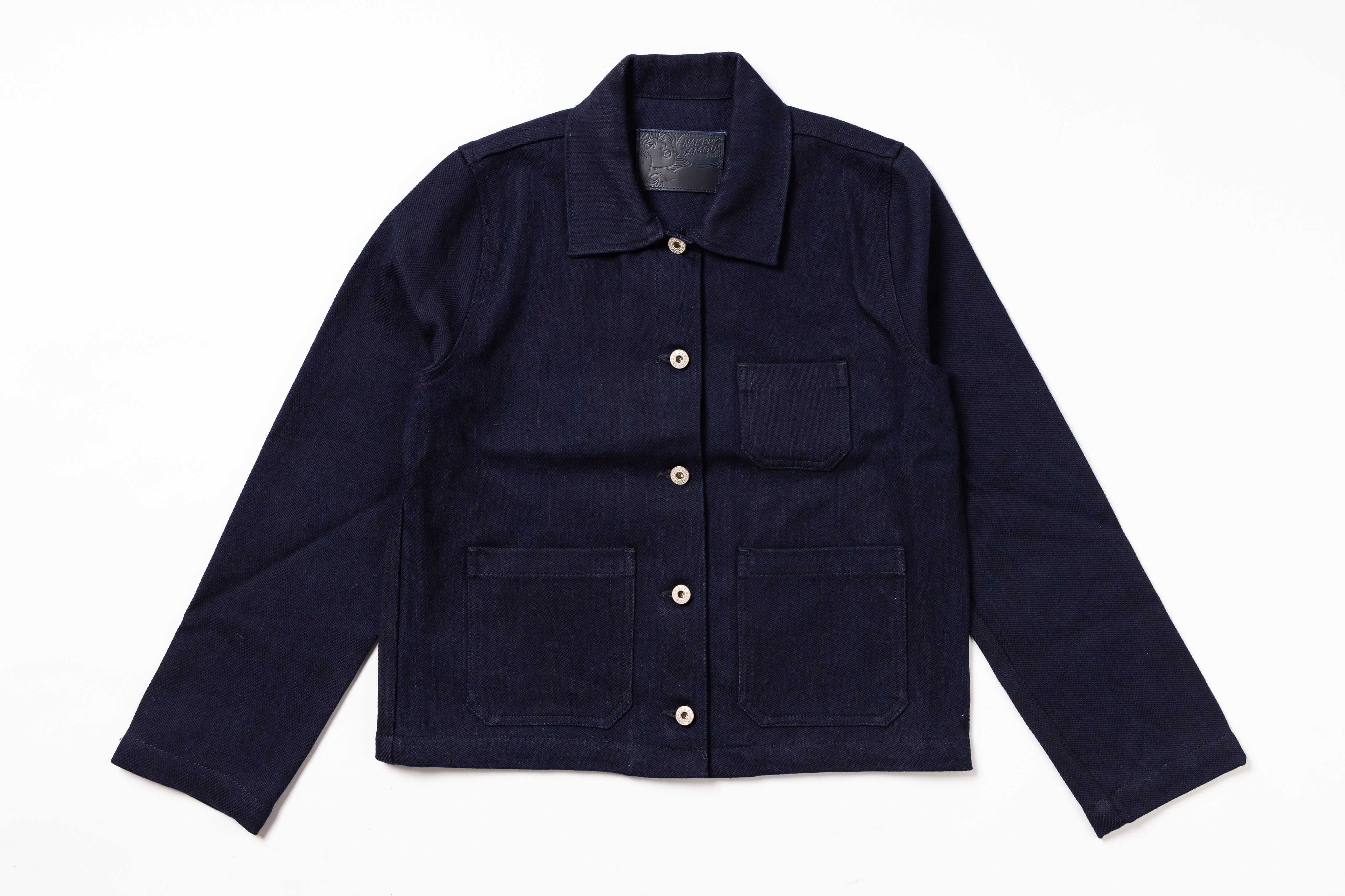 A dark navy blue corduroy utility jacket with a pointed collar, button front, and four front pockets, laid flat on a white background.