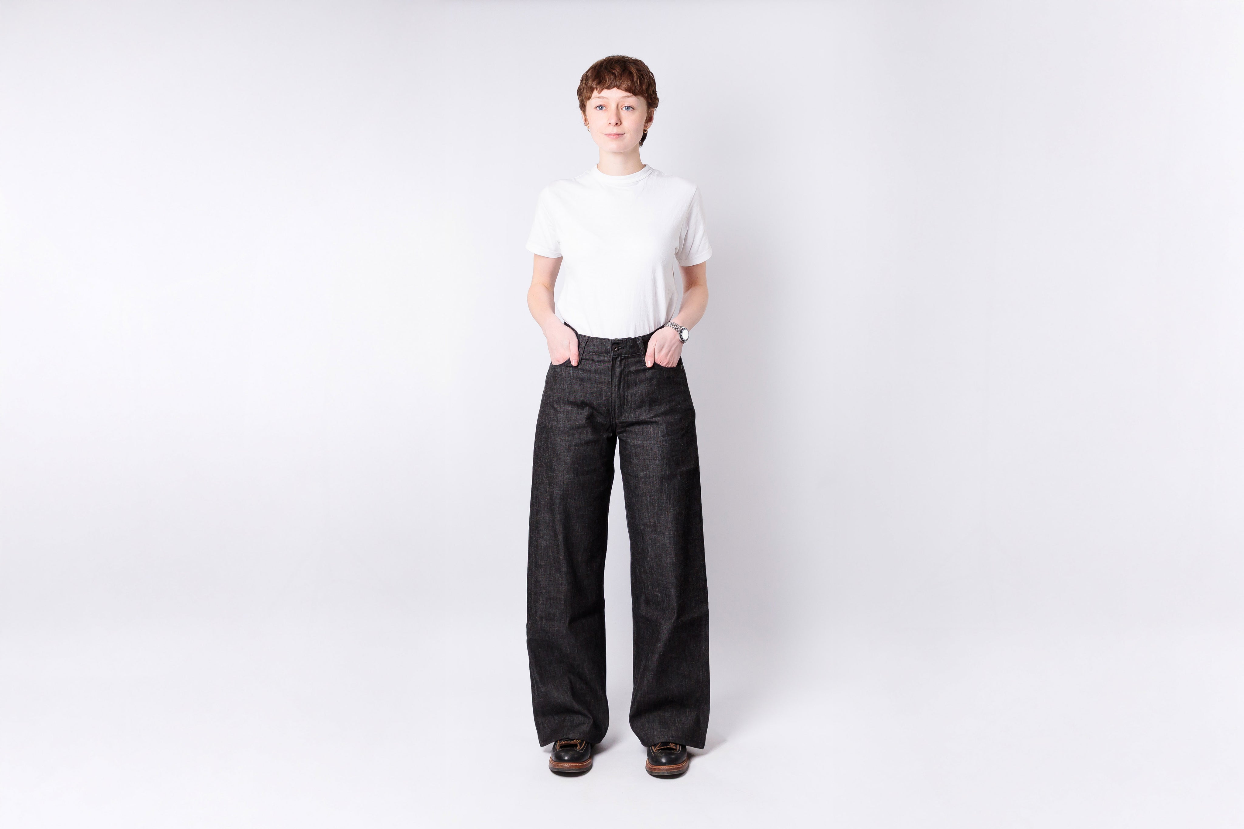 Person wearing a white shirt and dark pants on a white background