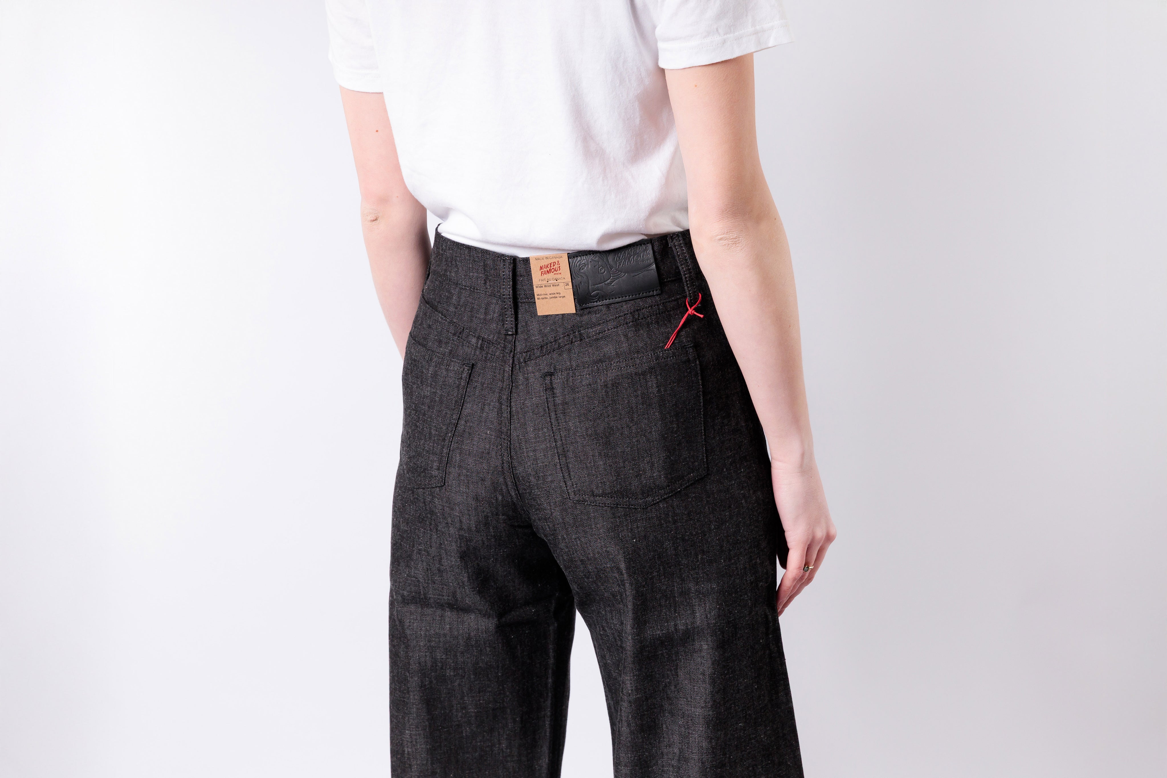 Person wearing dark gray pants with a visible brand label on a white background