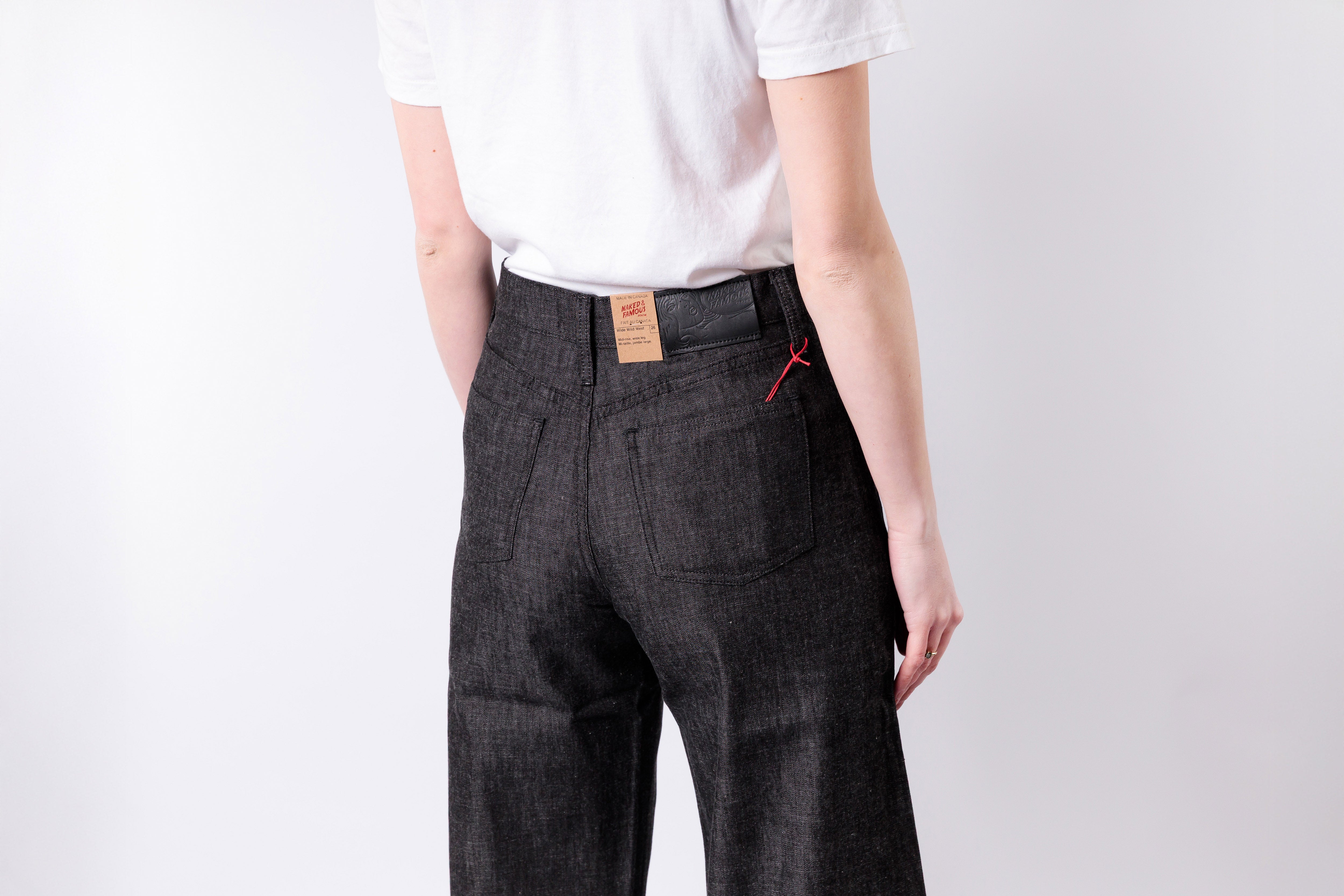 Person wearing dark gray pants with a visible brand label on a white background