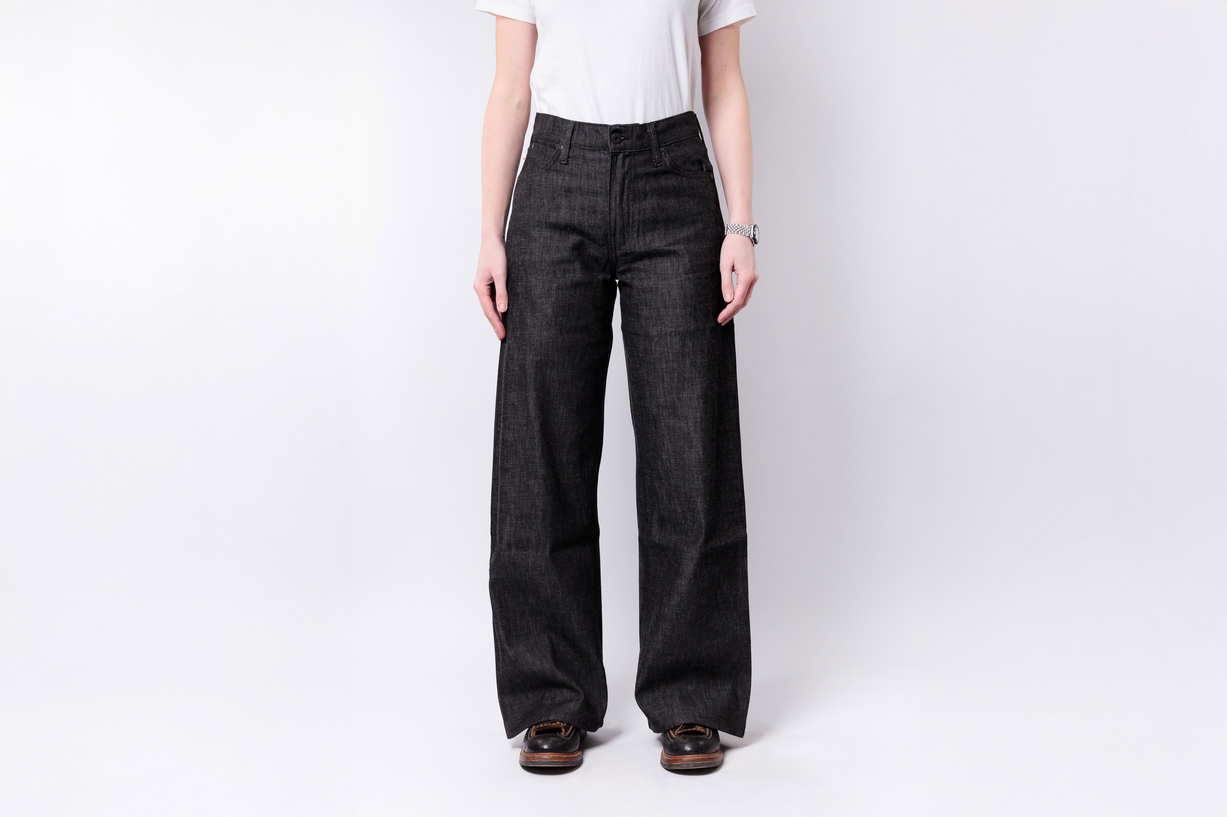 Person wearing black wide-leg jeans on a white background