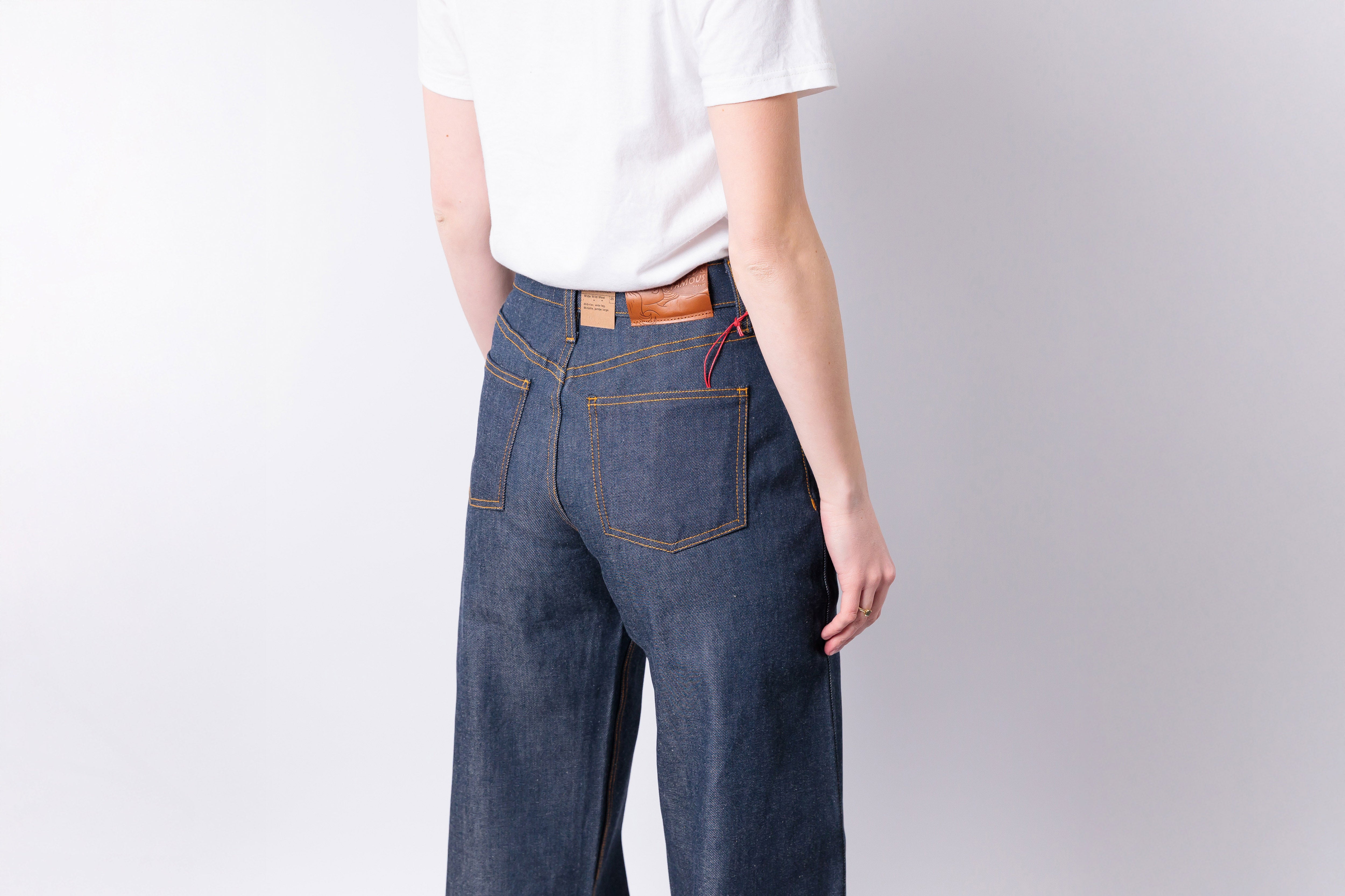 Person wearing blue jeans and a white shirt on a plain background