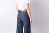 Person wearing blue jeans and a white shirt on a plain background