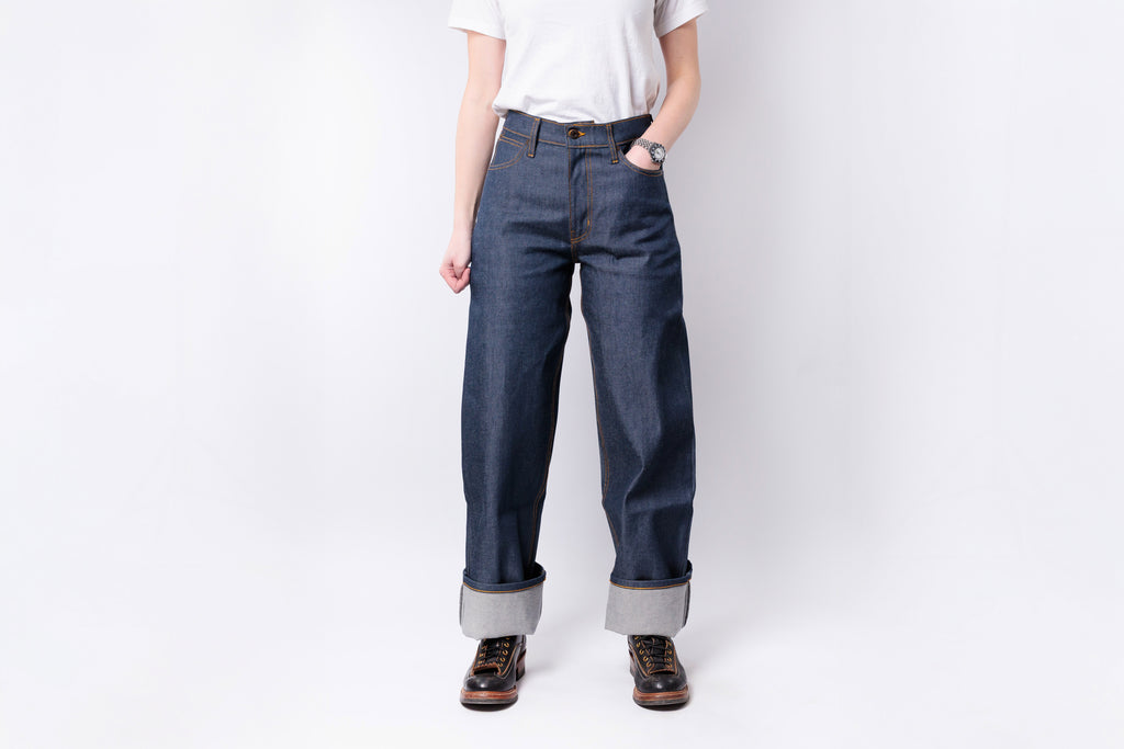 Person wearing blue jeans and a white shirt on a plain background