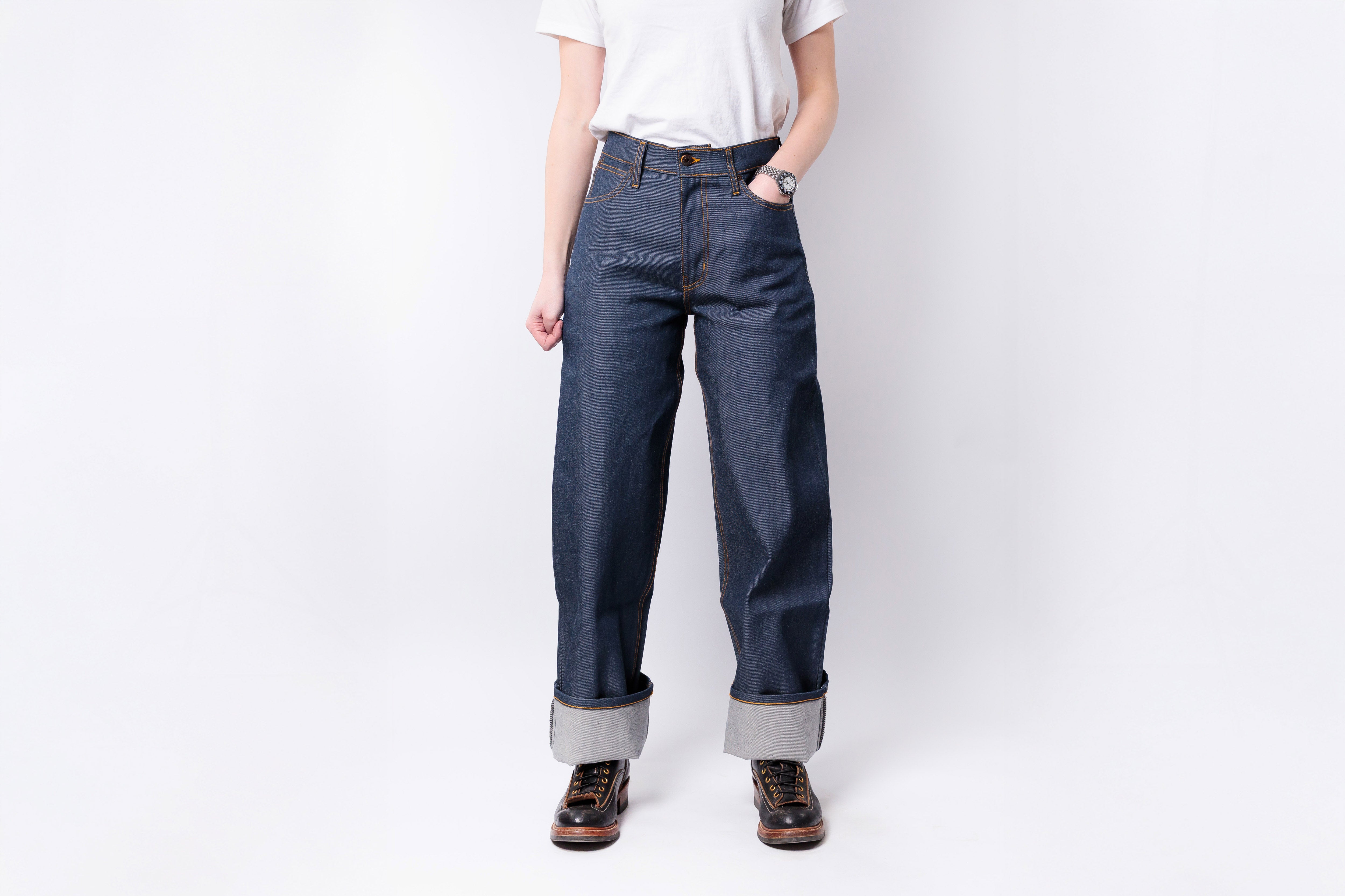 Person wearing blue jeans and a white shirt on a plain background