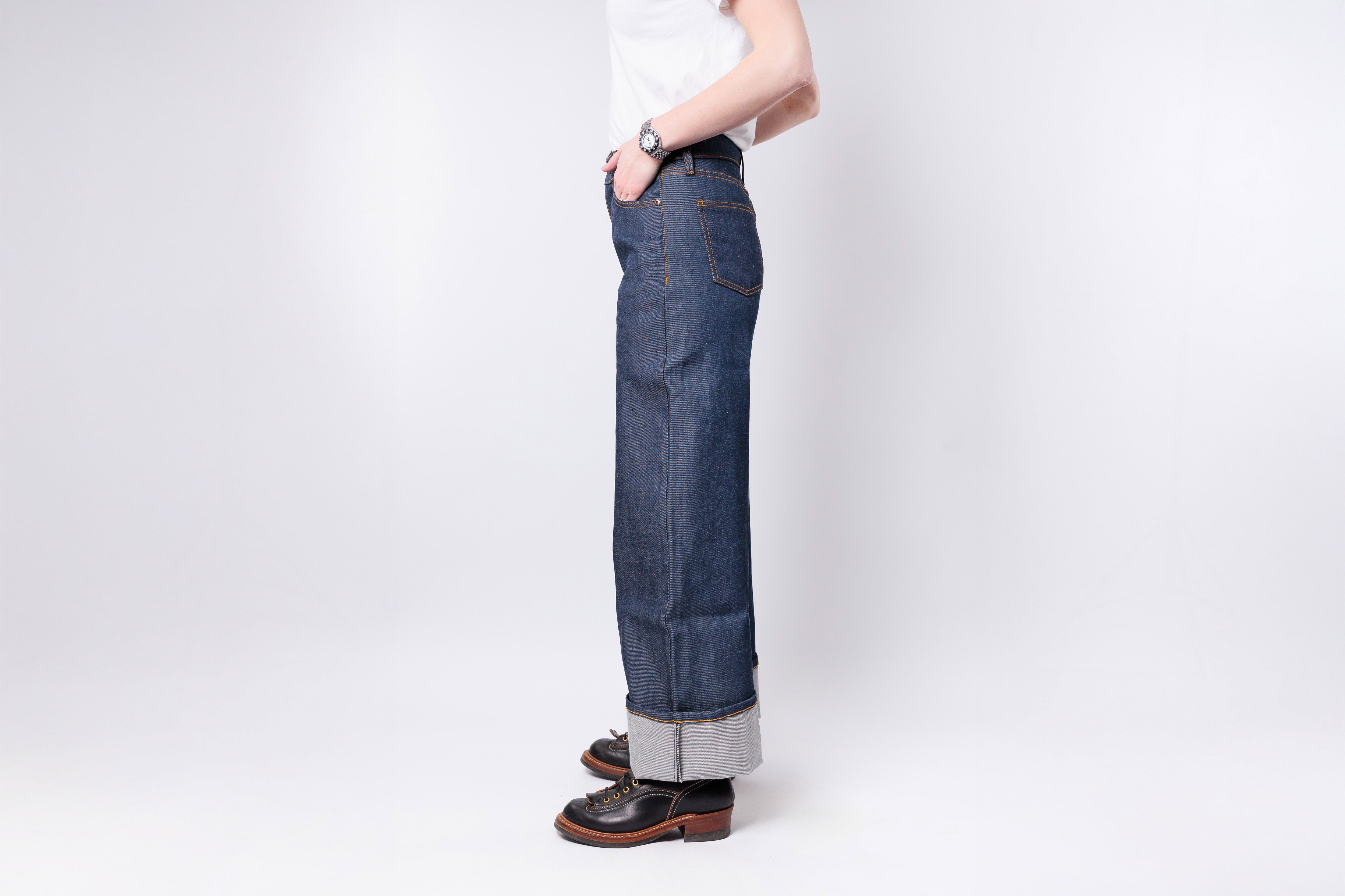 Person wearing blue jeans and a white shirt on a plain background